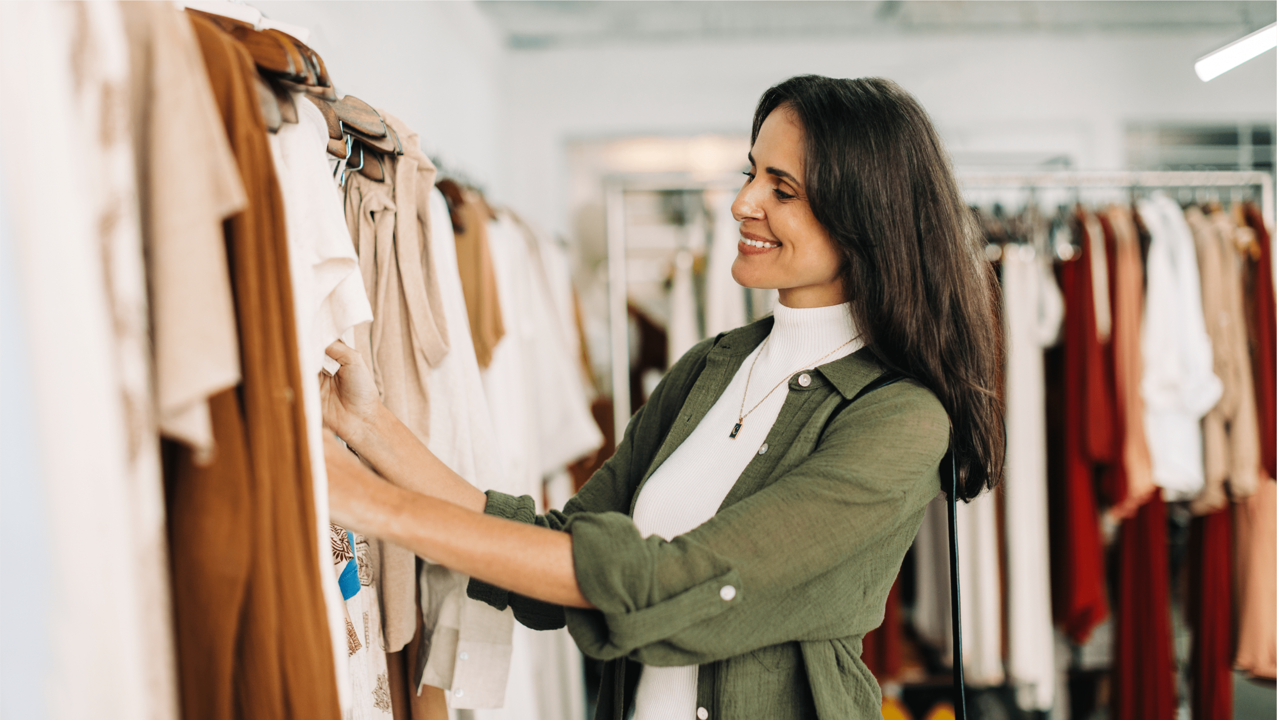 A woman arranging clothes in her shop.