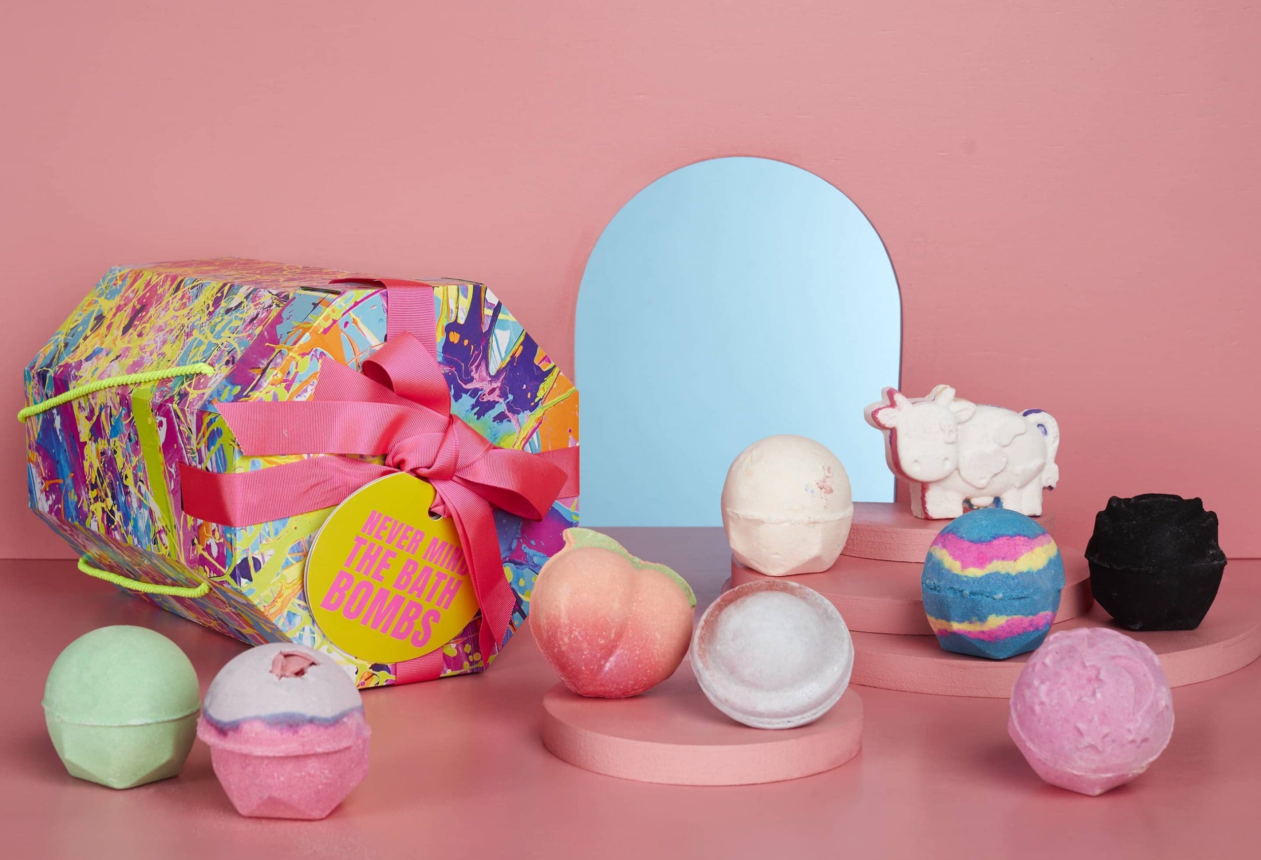 Colorful bath bomb set with a vibrant box, adorned with a pink ribbon. 