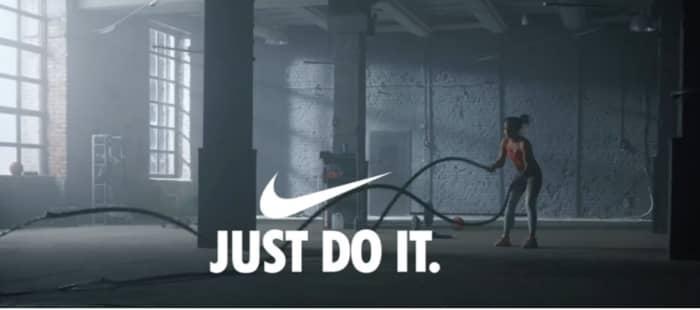 Nike “Just Do It” slogan with swoosh over athlete training.
