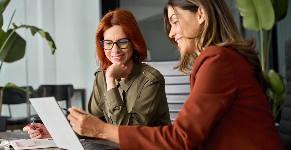 Two persons seated at a table, collaborating on a laptop, engaged in discussion and sharing ideas.