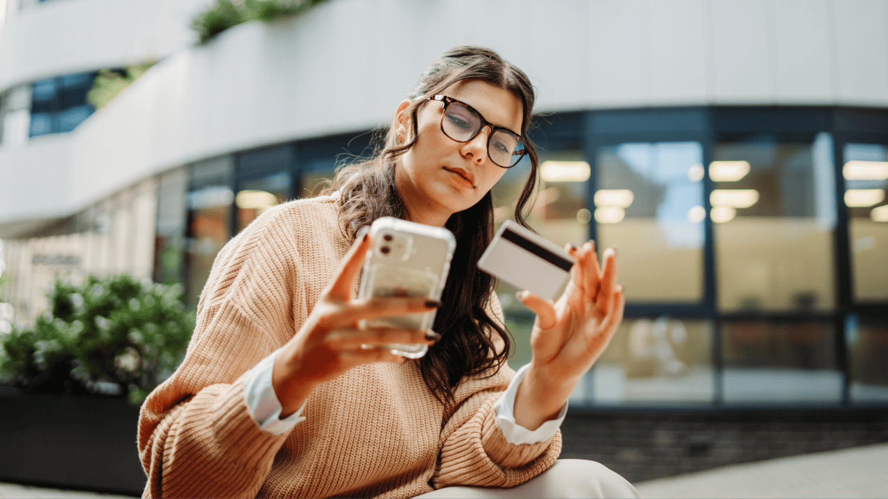 Woman using a smartphone and credit card to manage online payments with website security in mind.